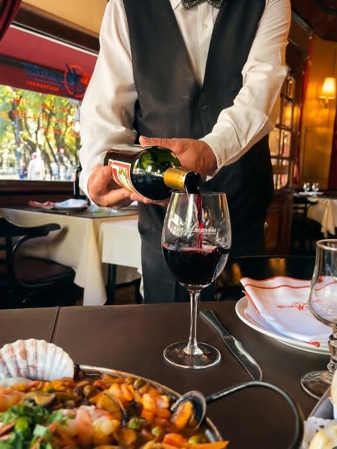 Un mozo sirve una copa de malbec