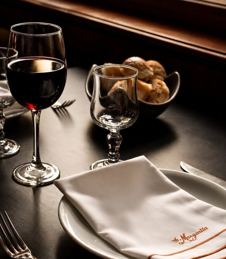 Una mesa servida, con copas y la servilleta bordada